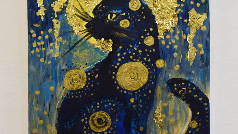 Obraz przedstawiający czarnego kota w profilu ze złotą aureolą. Mieni się złotem oraz granatem.