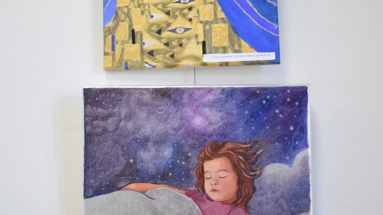 Dwa obrazki jeden pod drugim: Górny przedstawia kobietę w złotej ornamentowej sukni na niebieskim tle. Dolny obrazek przedstawia dziewczynkę śpiącą pod kołdrą - chmurą. W tle postaci widzimy rozmigotane, gwieździste niebo.