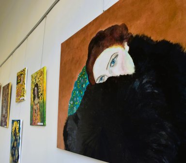 Obraz rudo-brązowowłosej, niebieskookiej kobiety o jasnej cerze, częściowo ukryta za czarnym futrem, które ją otula. Zza niej widzimy rude tło oraz fragment niebieskozielonej płaszczyzny pokrytej drobnymi obiektami - kwiatkami, ornamentami.