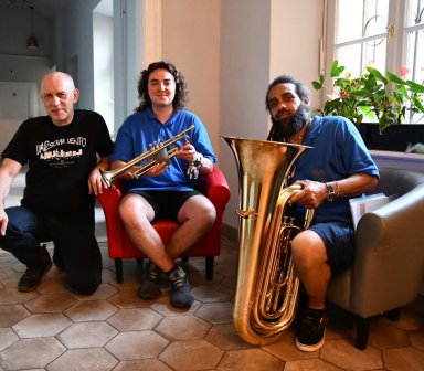 Trzech muzyków siedzi na fotelach, na korytarzu Centrum Kultury Podgórza.